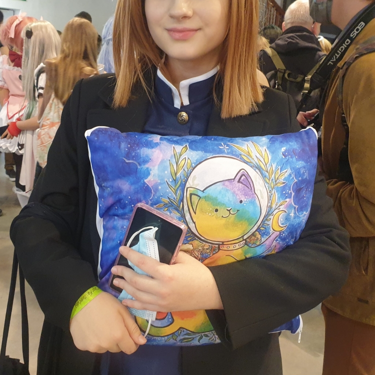 Dziewczyna przytula poduszkę z tęczowym kotem